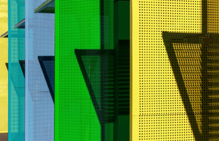 Vertically arranged perforated metal panels in vibrant colours, illustrating aesthetic versatility for creative installations.