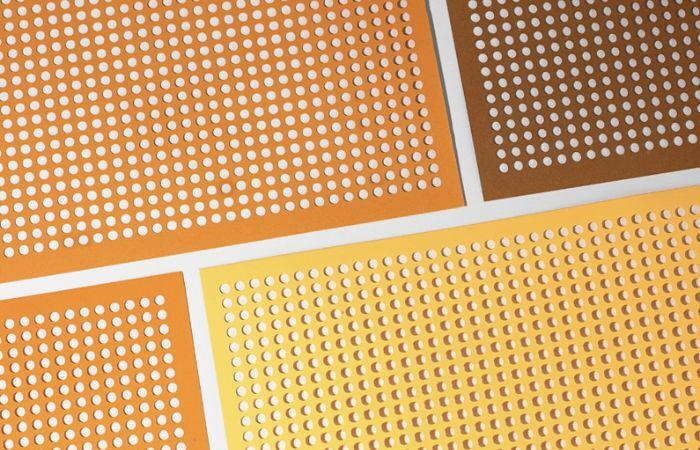 A detailed view of a metal sheet reveals a uniform pattern of round perforations.