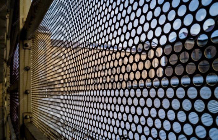 A detailed view of a metal sheet reveals a uniform pattern of round perforations.