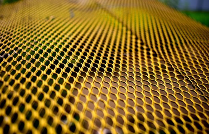 A vibrant yellow-coated expanded metal sheet, ideal for safety barriers, visual markers, or creative installations.